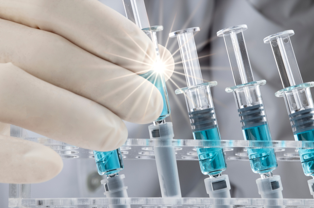 Doctor holding syringe filled with blue liquid
